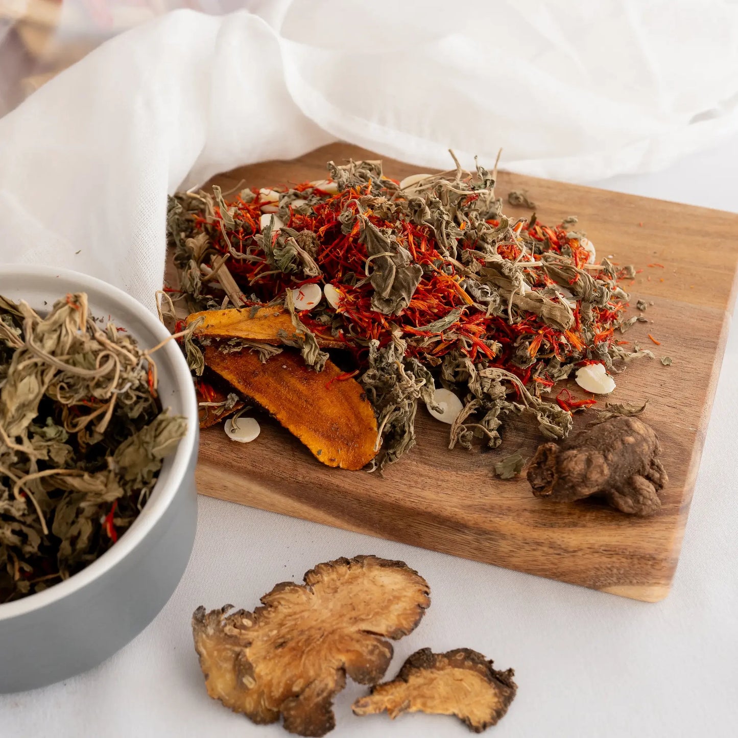 Dried postpartum recovery chibese herbs and roots on a wooden board and in a bowl.