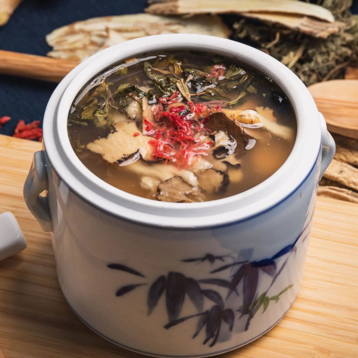 Traditional Chinese herbal soup for postpartum recovery in a ceramic pot on a wooden surface