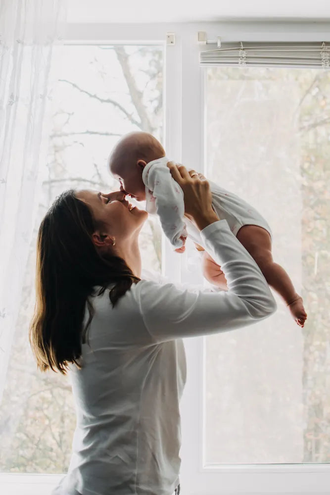 Woman holding a baby in front of a bright window
