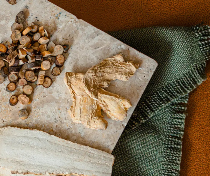 Confinement herbs on a stone surface with a green towel and brown fabric in the background.