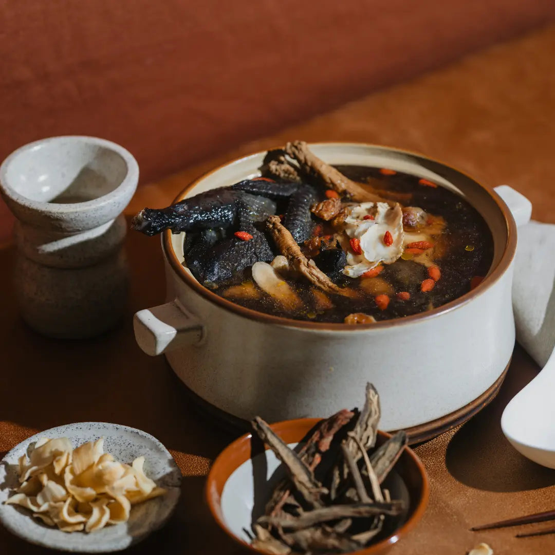 Ceramic pot with traditional Chinese confinement herbal soup on a wooden table