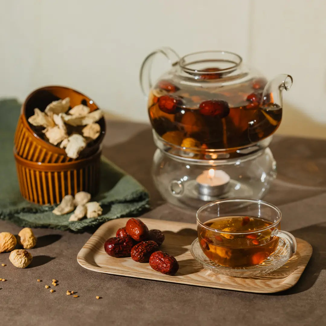 Teapot and cup of tea with dried fruits and nuts on a wooden tray