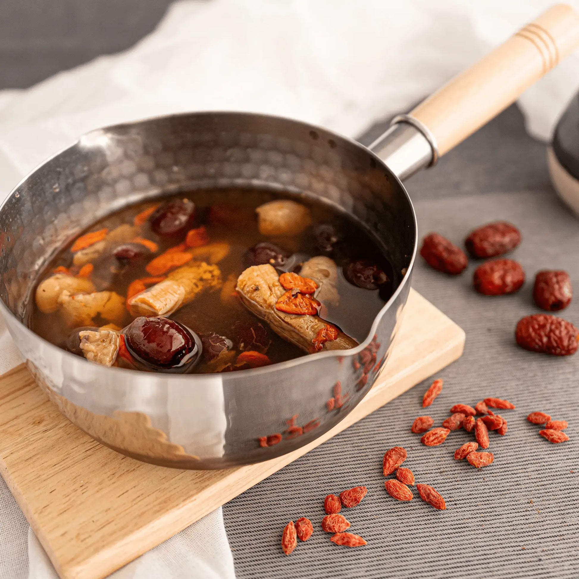 Pots of confiment red date tea with ingredients on a wooden board