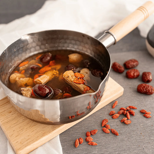 Pots of confiment red date tea with ingredients on a wooden board