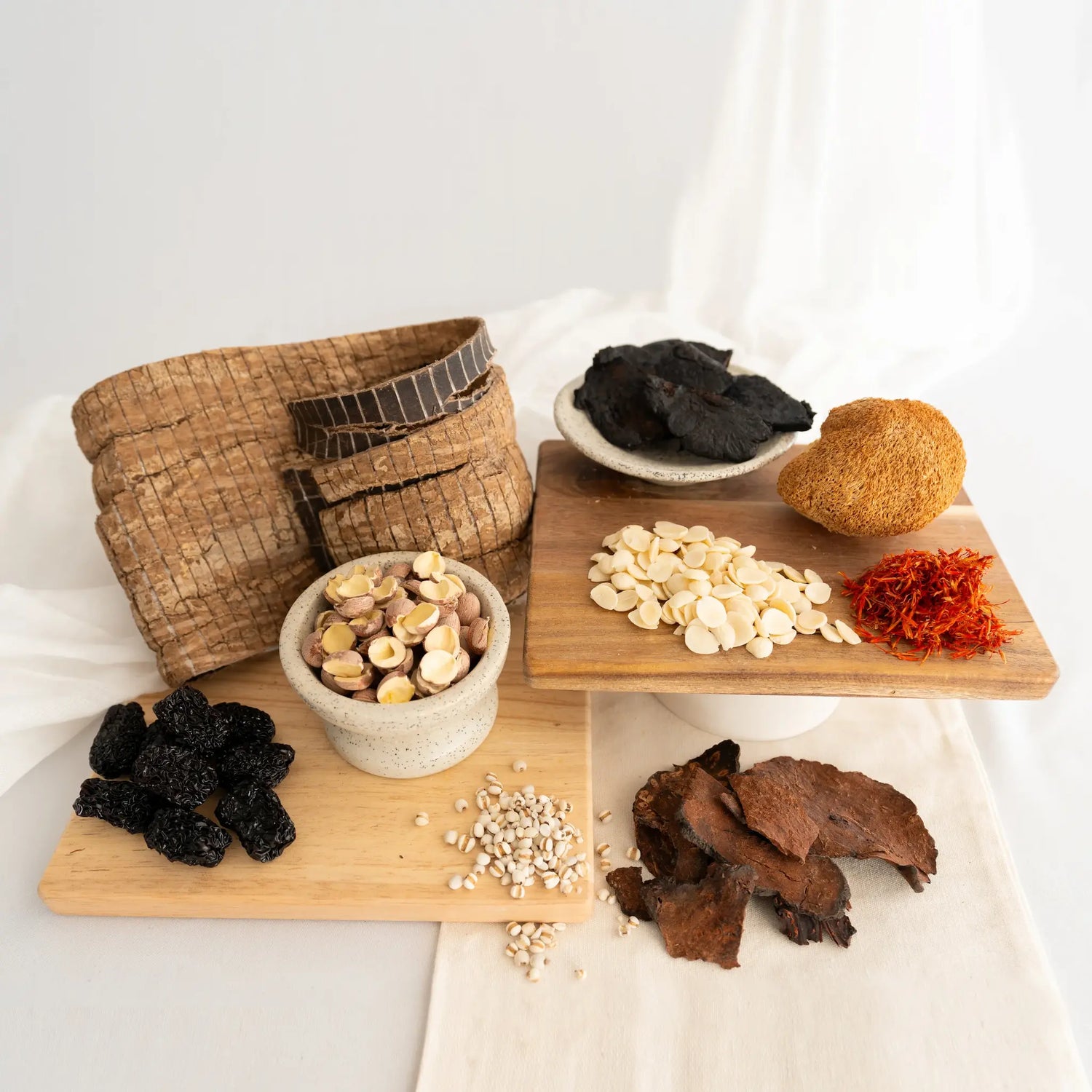 Assorted chinese postpartum herbs on wooden trays on a white background