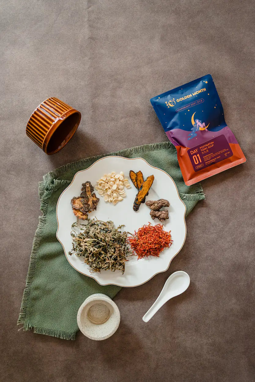 Dried confinement herbs on a plate with a Golden Month tea pack