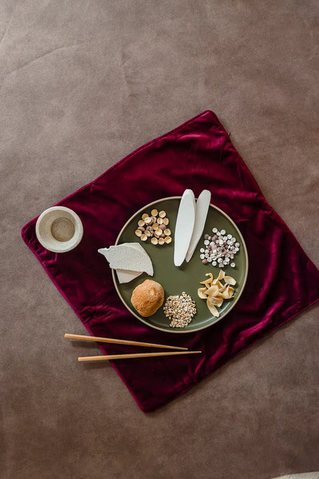 Green plate with Chiense confinement  herbs on a red velvet cloth against a brown background