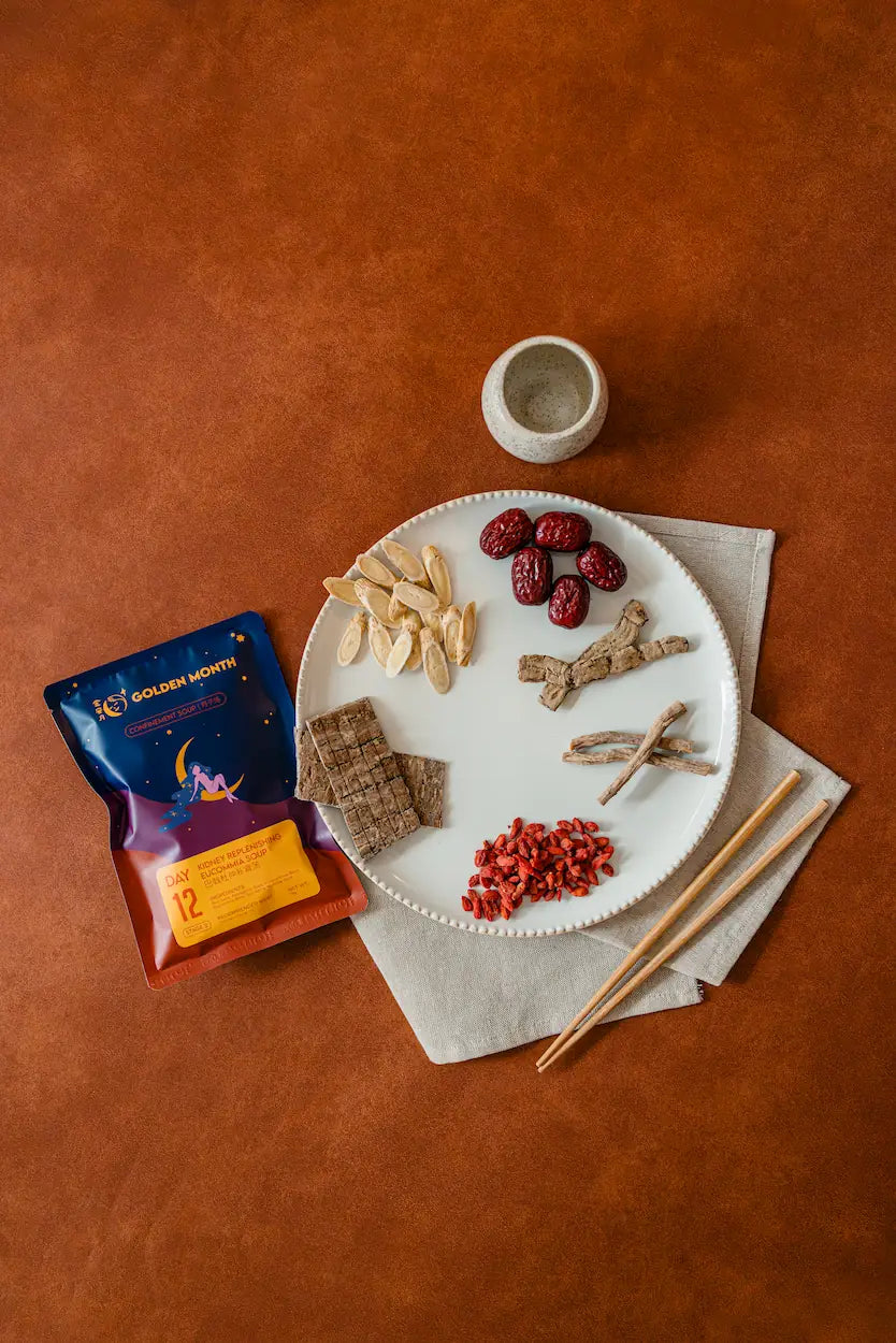 Dried fruits and nuts on a plate with a package of Golden Month tea on a brown surface.