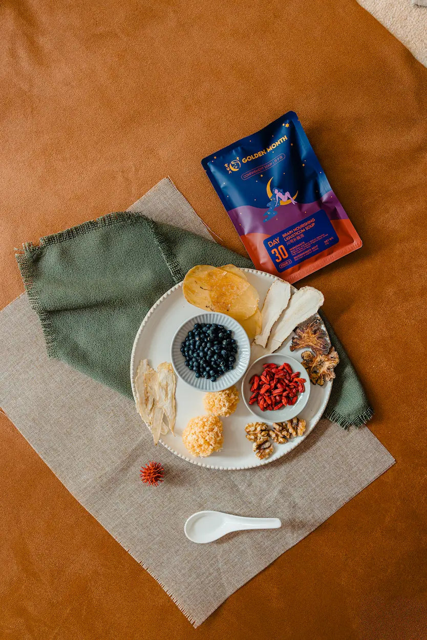 Assorted chinese herbs on a plate with a package of tea on a brown surface