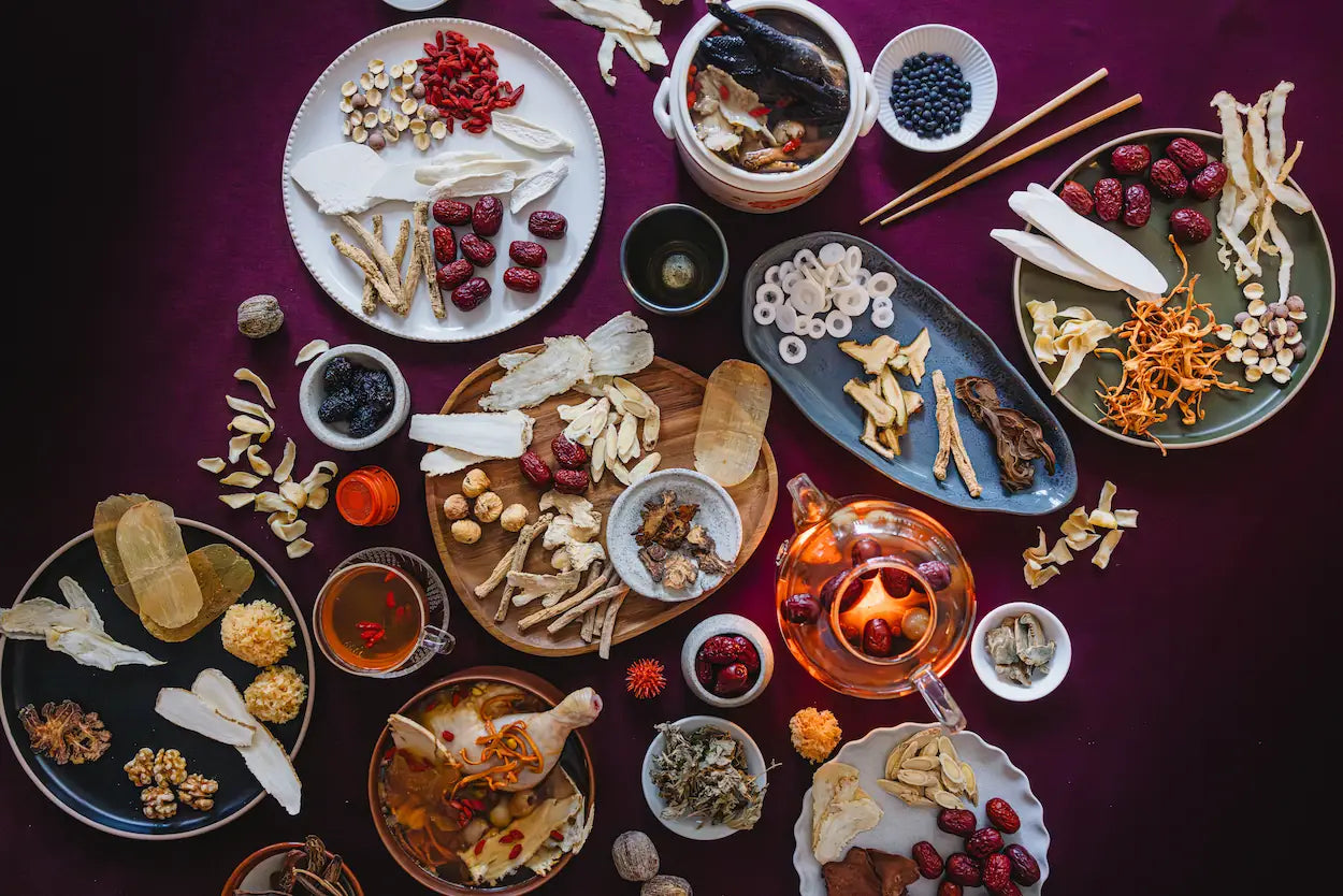 Assorted dried fruits, nuts, and herbs on plates with a warm glow on a dark background