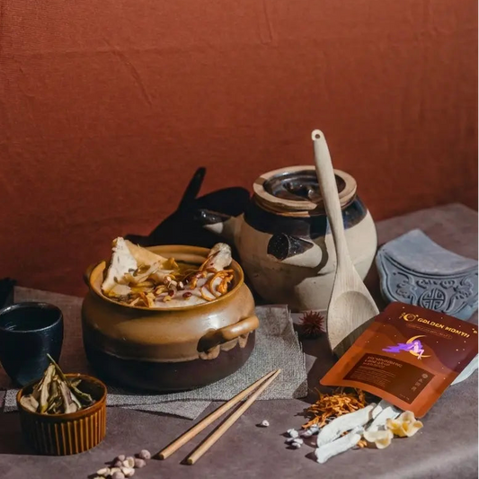 Tea-making setup with ceramic pots, tea leaves, and packaging on a wooden surface.