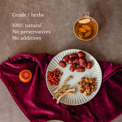 Confinement herbs on a plate with a cup of tea on a maroon fabric background
