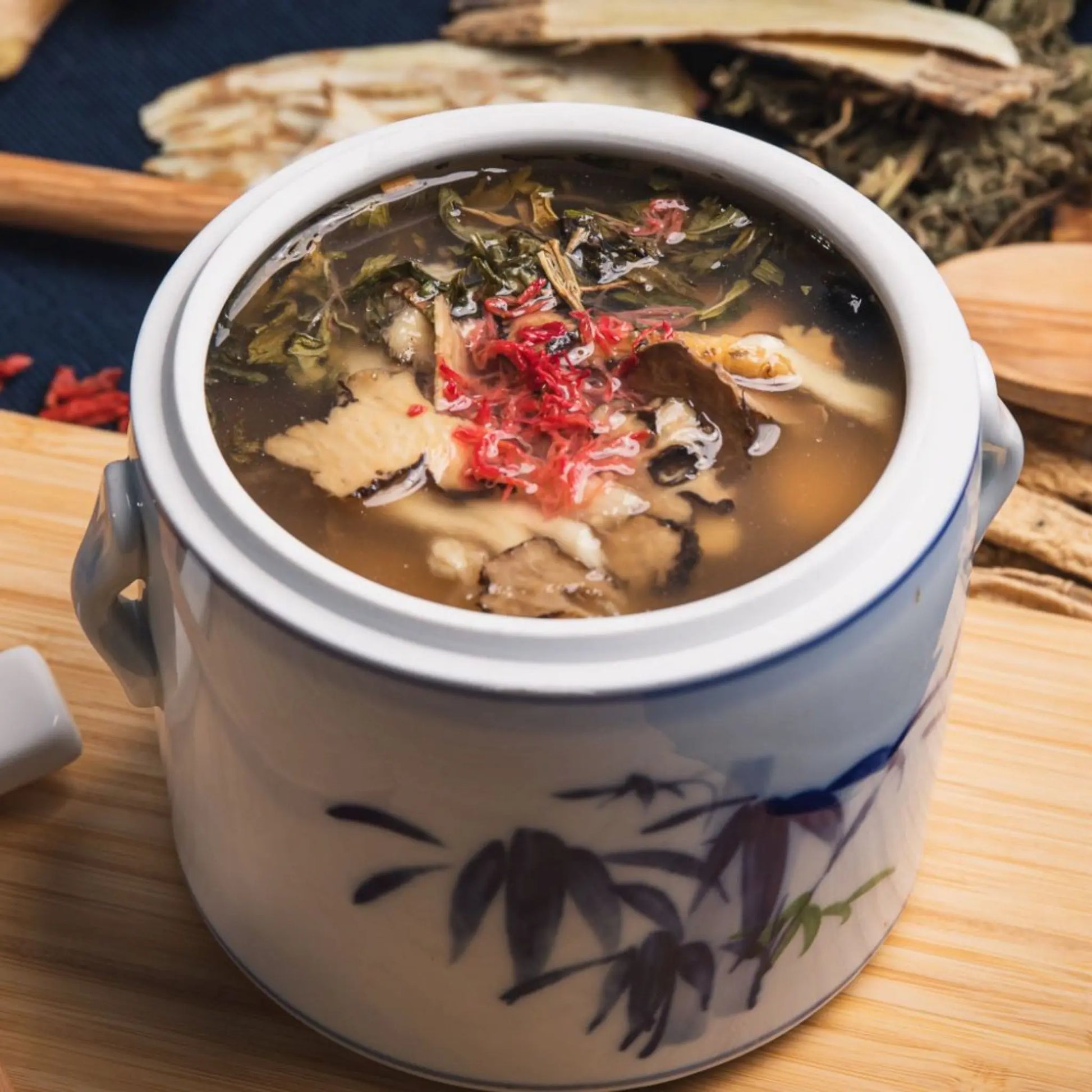 Traditional Chinese herbal soup for postpartum recovery in a ceramic pot on a wooden surface